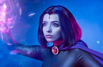 Woman wearing a complete dark purple Teen Titans Raven cosplay costume with hooded cape and red gem