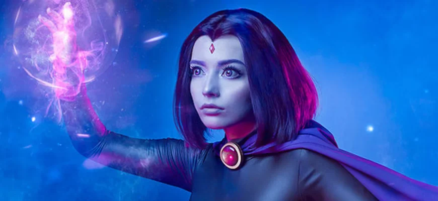 Woman wearing a complete dark purple Teen Titans Raven cosplay costume with hooded cape and red gem